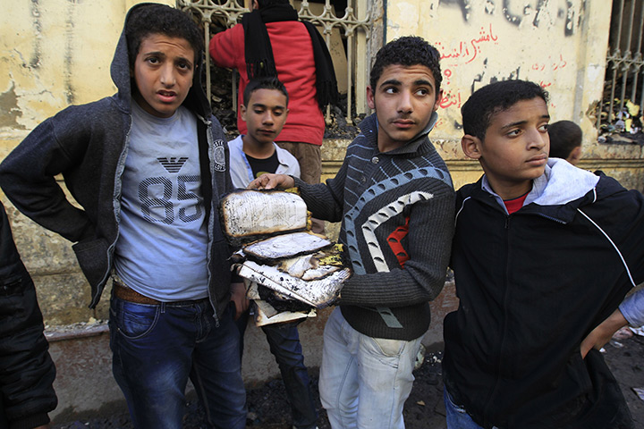 Cairo clashes: Egyptian boy holds a burnt manuscript after the Institute of Egypt burned