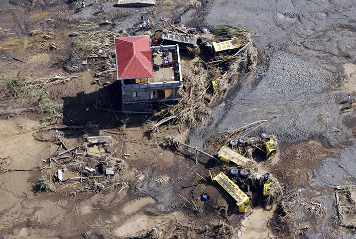Philippines flooding: Dump trucks lie in mud on the compound of a house damaged by flash floods 