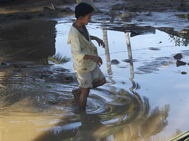 24 hours: Iligan city, Philippines: A resident wades through mud in his front yard