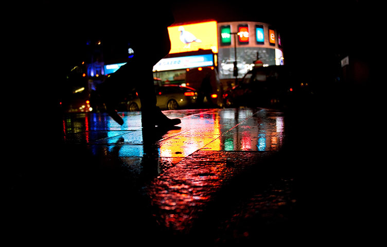 24 hours in pictures: London, UK: A man walks through the rain in Piccadilly Circus