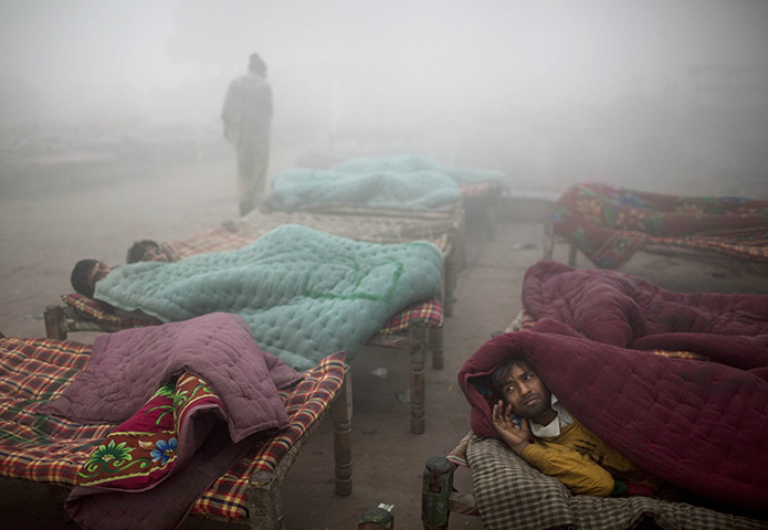 24 hours in pictures: Indian migrant workers lay on rented cots in dense fog in New Delhi