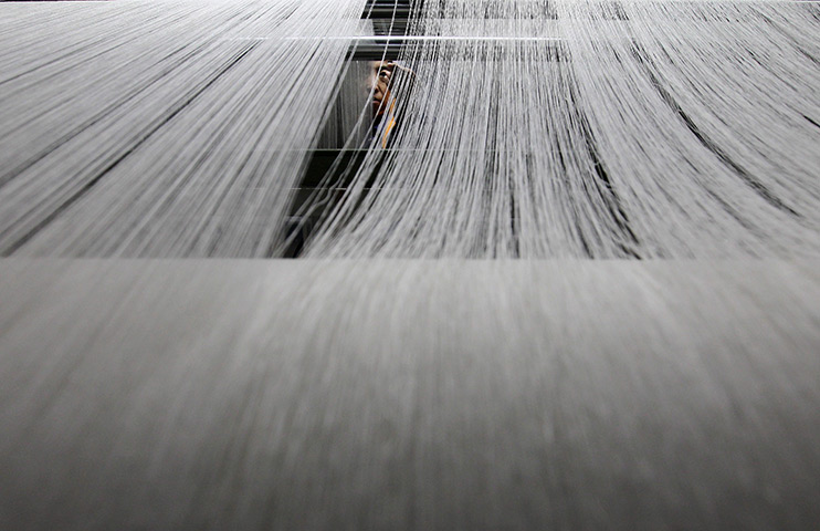 24 hours in pictures: A Chinese factory worker operates a loom at a textile manufacturing factory