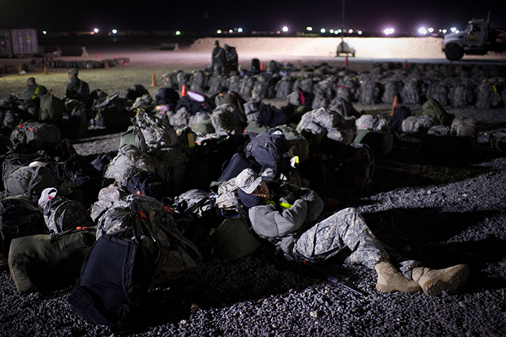 24 hours in pictures: A US soldier sleeps amid backpacks as he waits to head home from Iraq