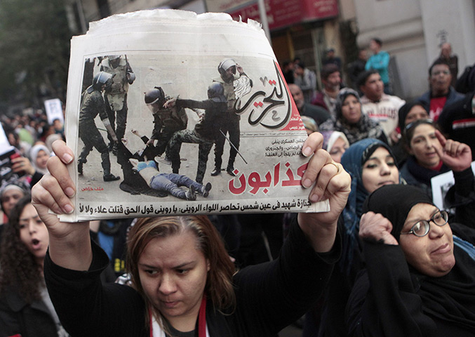 women protest in cairo: A woman raises a copy of Al Tahrir newspaper 