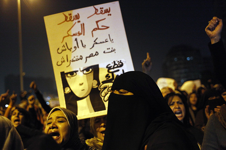 women protest in cairo: A protester carries a poster 