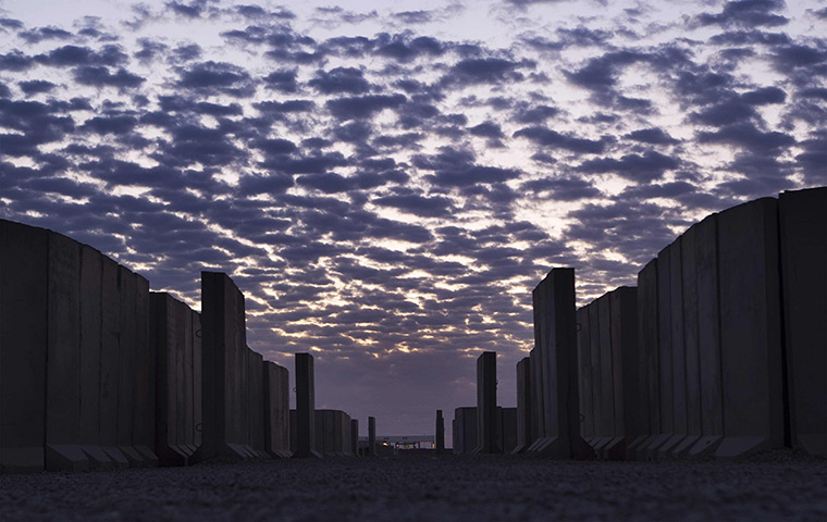 FTA: Lucas Jackson: The sun rises behind an alleyway lined with blast walls inside Camp Adde