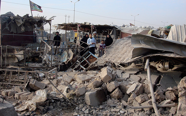 Iraq bombing: Residents gather at the site of a bomb attack in Baghdad's Shula district