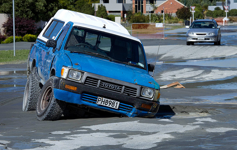 Christchurch earthquake: A car is trapped in the middle of the road in a sink hole