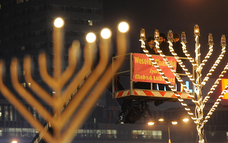 Hanukkah: Rabbi Shalom Ber Stambler lights a candle on a large menorah in Warsaw