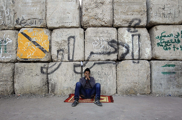 24 hours in pictures: Cairo, Egypt: An Egyptian protester sits in front of a cement barricade