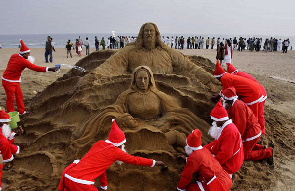 24 hours in pictures: Bhubaneswar, India: Artists dressed as Santa Claus create a Santa Claus sculpture