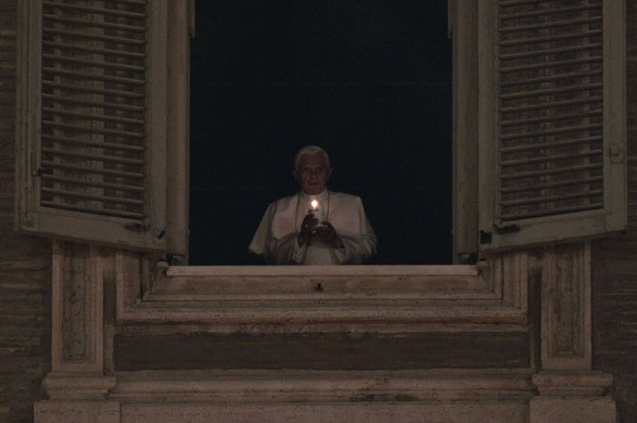 24 hours in pictures: Vatican City: Pope Benedict XVI holds up a candle at the window of his private apartment to celebrate the unveiling of the nativity scene in Saint Peter's Square