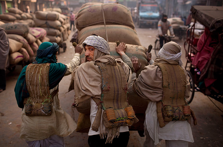 24 hours in pictures: Labourers push a cart of dried dates at a market  in Delhi