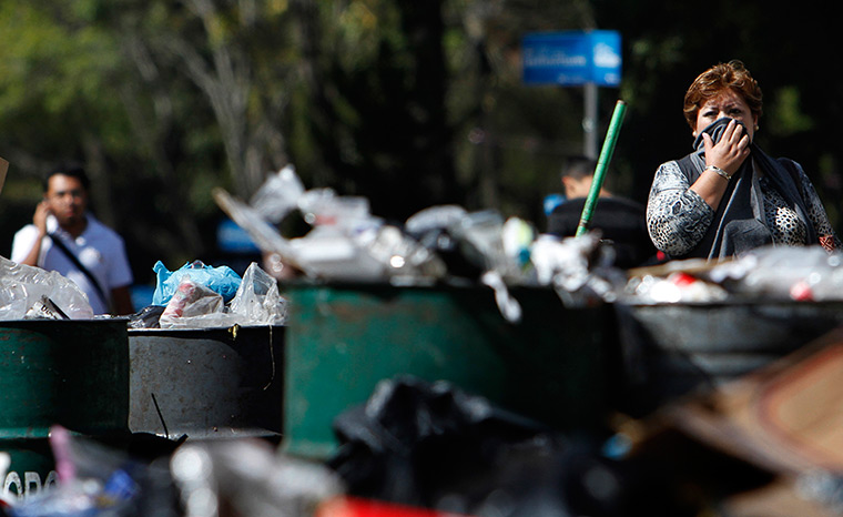 24 hours in pictures: A woman covers her face as she walks past piled up rubbish in Mexico