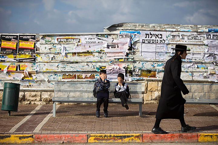24 hours in pictures: Two Ultra-Orthodox Jewish boys cover their faces as a man passes, Israel