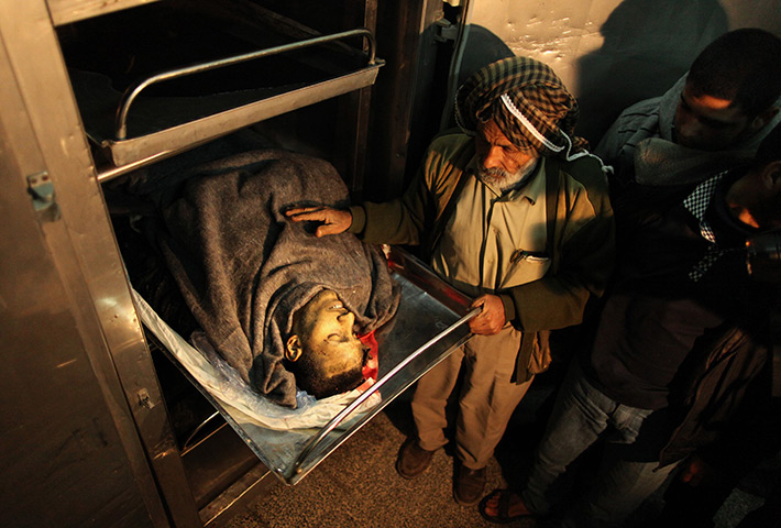 24 hours in pictures: Gaza Strip: People stand next to the body of a man killed in an explosion