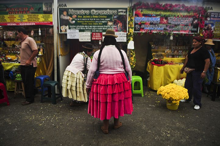 24 hours in pictures: Lima, Peru: An Andean woman stands in front of a stand at the Wishes Market
