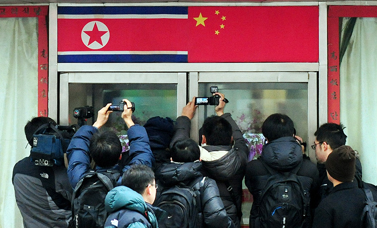 24 hours in pictures: Dandong, China: Journalists try to see of mourners in a restaurant 