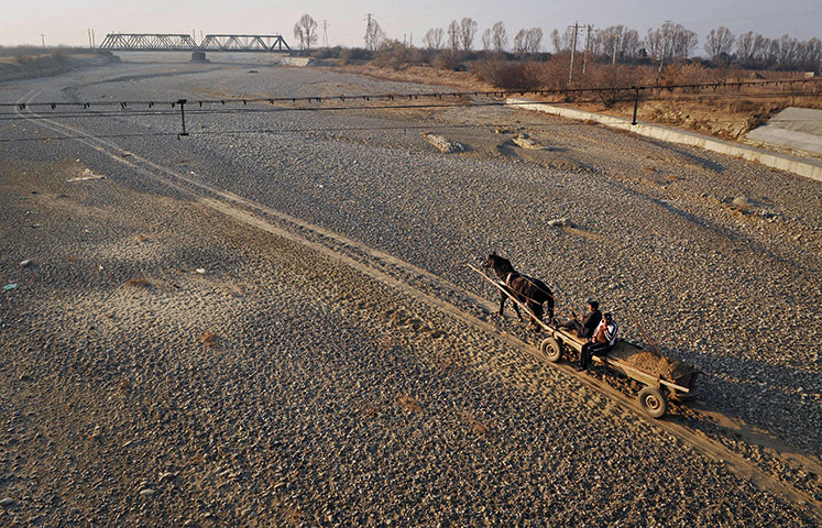 24 Hours: Men drive a horse pulled cart along the dried river bed of Susita river