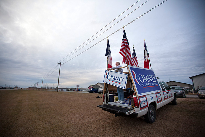 Iowa campaigning: A supporter of Mitt Romney puts up signs at a campaign stop in Ames, Iowa