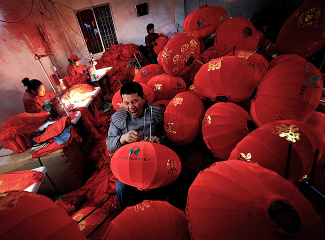 New year preparations: Yaxi village, China:  A man yawns as he makes red lanterns
