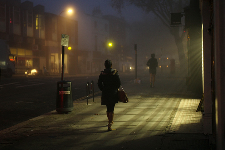 from the agencies: A woman and a jogger on a foggy Hampstead High Street in north London 