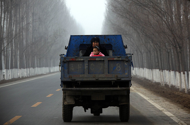 24 hours in pictures: A woman sits with her daughter on the back of a truck in  Baoding
