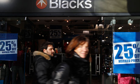 People pass a Blacks store with sale signs in the window in central London