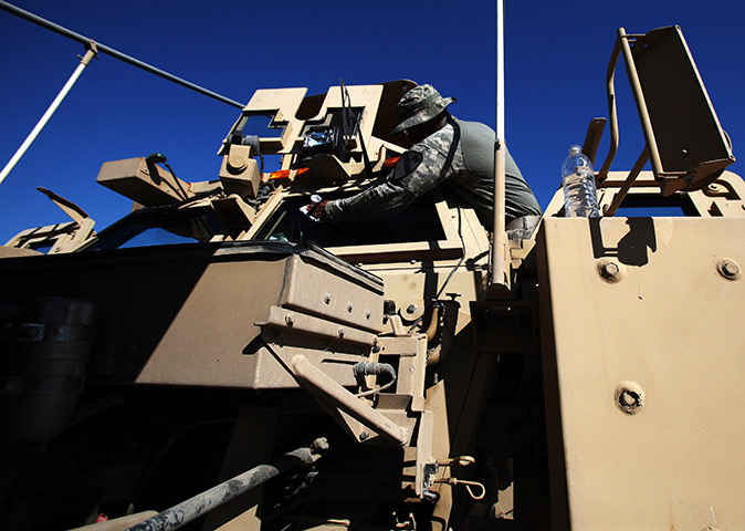 24 hours in pictures: US Army Specialist cleans the windshield of his vehicle , Iraq