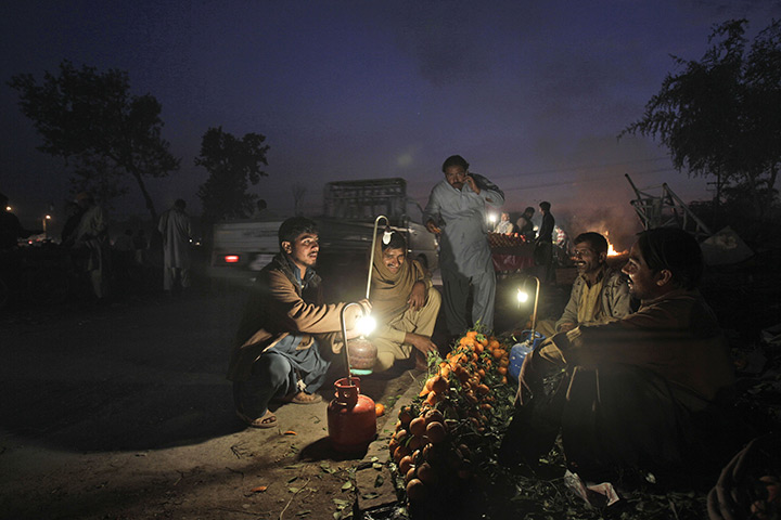 24 hours in pictures: Pakistani fruit vendors sit on a roadside waiting for customers