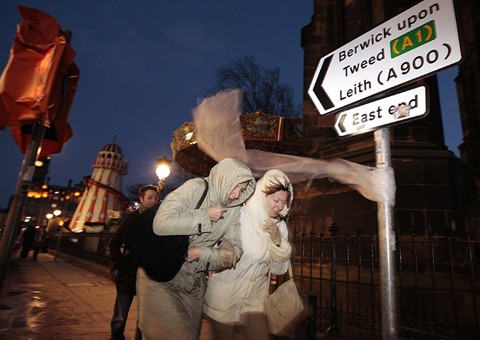 UK weather: Two women link arms as they walk in strong winds in Edinburgh