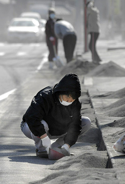 Shinmoedake volcano Japan: People remove volcanic ash from a road in Miyakonojo city, Japan