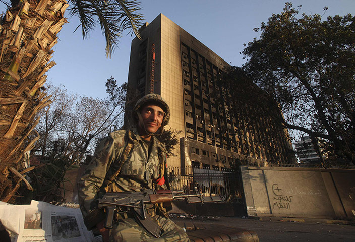 Egypt protests: An Egyptian soldier near the burnt National Democratic party building