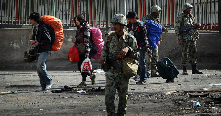 Egypt protests: Tourists pass soldiers and debris as they walk through the streets of Cairo