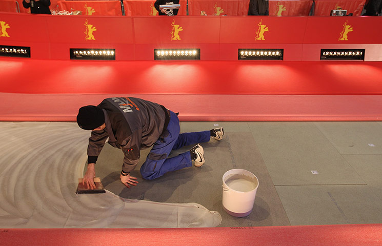 24 hours in pictures: A worker spreads glue to lay the red carpet, Berlin