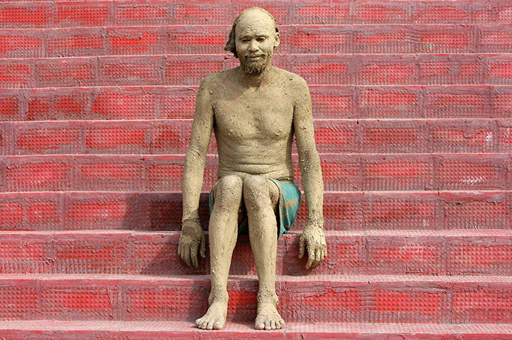 24 hours in pictures: A devotee sits as he lets the mud on his body dry and harden in Chamliyal