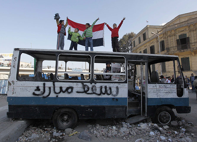 Egypt Day 19: Egyptian boys stand atop a destroyed bus in Tahrir Square