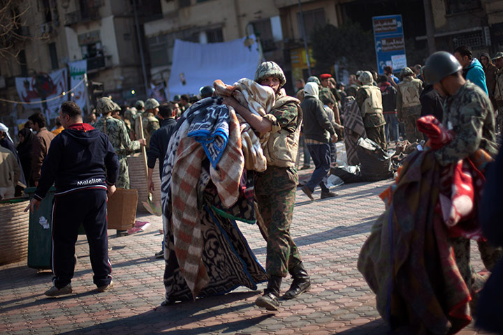 Egypt aftermath: An Egyptian Army soldier removes the blankets from protesters