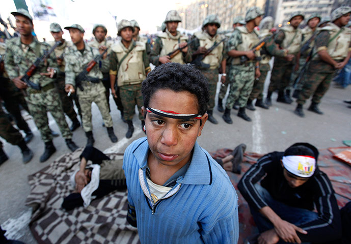 Egypt aftermath: An Egyptian protester boy stands in front of army soldiers