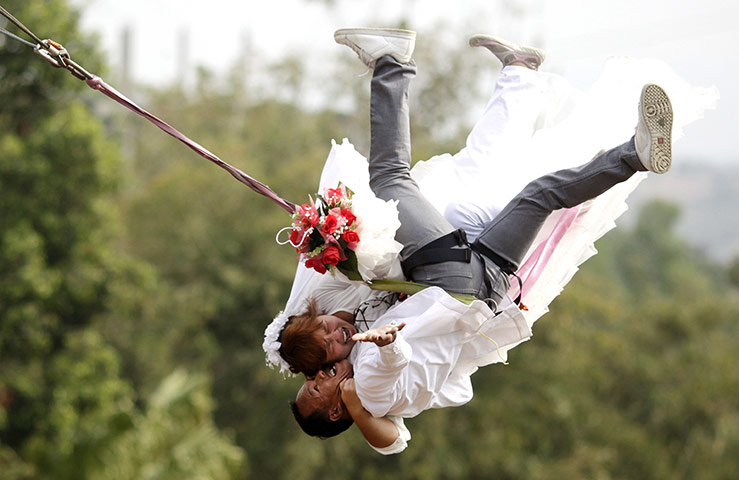 Valentine's Day: Prachinburi province, Thailand: A couple swing out on rappelling ropes