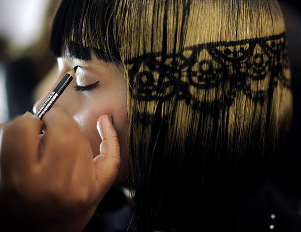 New York Fashion Week: A model with stenciled hair has makeup applied
