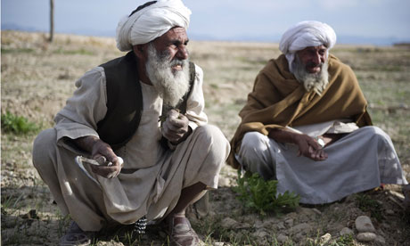 Afghan farmers work in a field as unseen