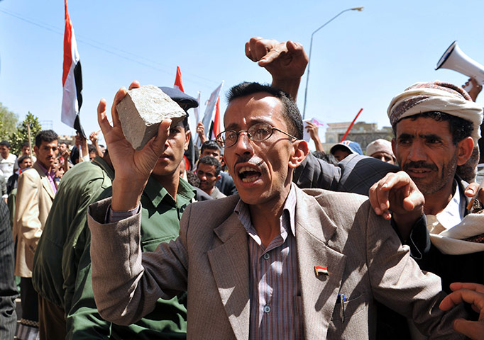 Protests spread: Sana'a, Yemen: A government supporter holds a stone 