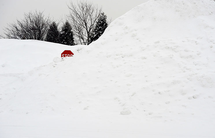 US White Out: A stop sign pokes out of a pile of snow
