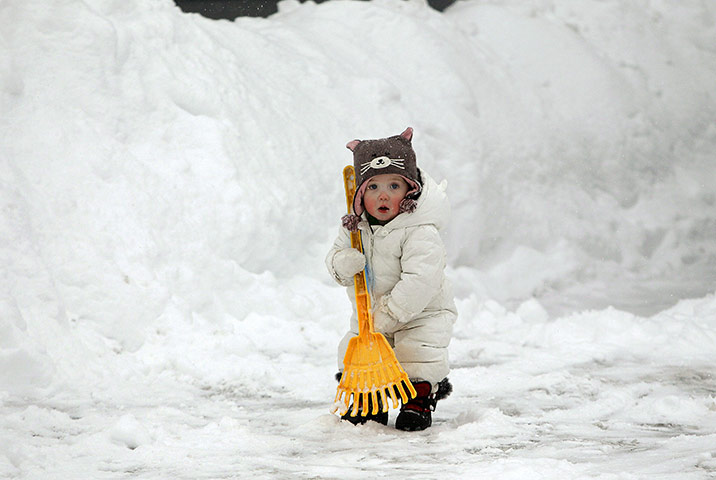 US White Out: A child helps her mom shovel snow