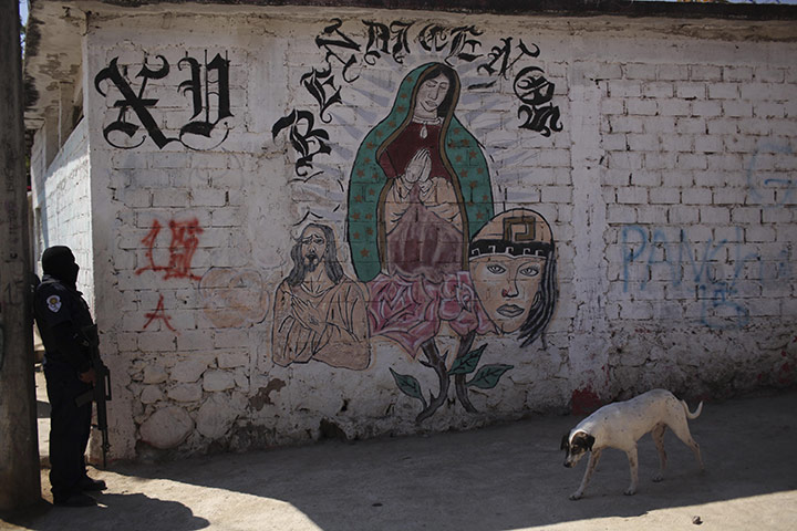 FTA Alexandre Meneghini: A police officer stands by a mural depicting religious figures in Acapulco