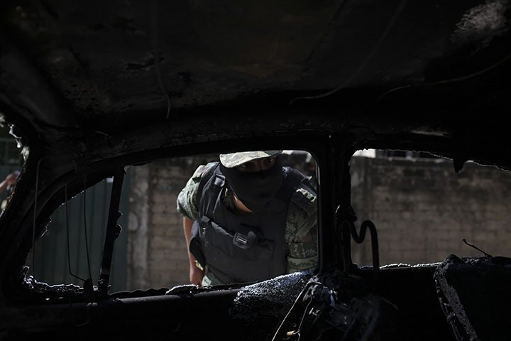 FTA Alexandre Meneghini: A Mexican army soldier inspects a burned car in a neighbourhood of Acapulco