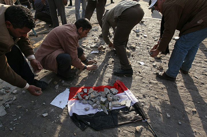 Egypt clashes day 9: Anti-government protestors place broken paving stones on an Egyptian flag