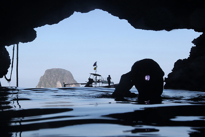 24 hours: Muk Island, Thailand: A cave tourist shines a torch at the Emerald Cave 