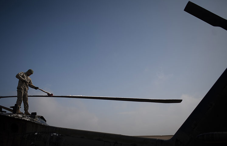 24 hours: Kunduz, Afghanistan: A US Army soldier cleans snow off a helicopter